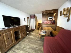 een woonkamer met een flatscreen-tv en een bank bij Résidence Cote Brune - Studio pour 4 Personnes 114 in Les Menuires