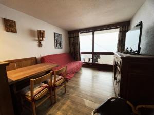 een woonkamer met een tafel en een rode bank bij Résidence Cote Brune - Studio pour 4 Personnes 114 in Les Menuires