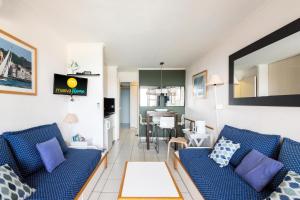 un salon avec deux canapés bleus et une cuisine dans l'établissement Résidence le Hameau de Cap Esterel - maeva Home - Studio 5 Personnes - Sél 944, à Saint-Raphaël