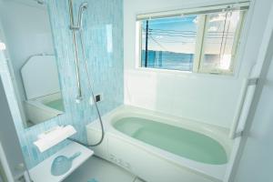 ein Bad mit einer Badewanne, einem Waschbecken und einem Fenster in der Unterkunft HOMIE TERRACE Funakata in Tateyama