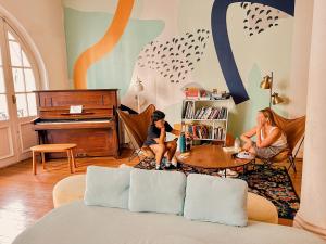 uma criança sentada numa mesa numa sala de estar com um piano em Viajero Montevideo Hostel em Montevidéu