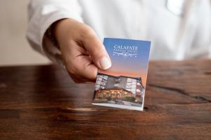 a person holding up a book on a table at Calafate Parque Hotel in El Calafate