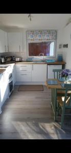 a kitchen with white cabinets and a table and a sink at Leigh’s Lodge in Colyford