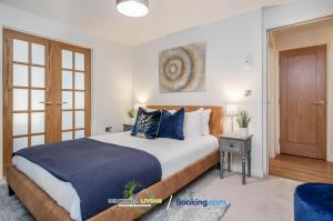 a bedroom with a large bed with blue pillows at Windsor, 2 Bedroom Apartment By Sentinel Living Short Lets & Serviced Accommodation Windsor Ascot Maidenhead With Free WiFi in Windsor