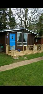 a house with a wooden deck with a blue door at Leigh’s Lodge in Colyford