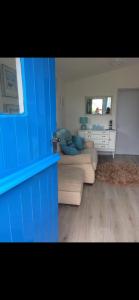 a living room with two couches and a blue wall at Leigh’s Lodge in Colyford
