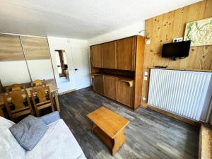 ein Wohnzimmer mit einem Bett, einem TV und einem Tisch in der Unterkunft Résidence Lac Du Lou - Studio pour 4 Personnes 214 in Les Menuires