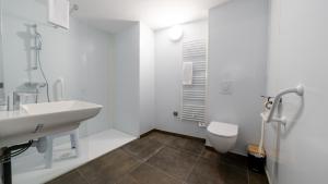 a white bathroom with a sink and a toilet at Hôtel Des Docks in Digoin
