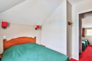 um quarto com uma cama verde num quarto branco em La résidence du Lac - maeva Home - Maison 3 Pièces 6 Personnes - Confort 764 em Monflanquin