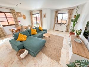 a living room with a green couch and a table at Villa Tarabilla with private pool & ocean views in Corralejo