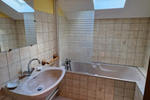 ein Badezimmer mit einem Waschbecken und einer Badewanne in der Unterkunft Au Petit Petonfaing in Le Syndicat