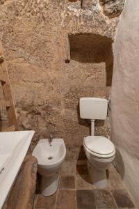 Baño de piedra con aseo y lavamanos en Case degli Avi 2, antico abitare in grotta, en Módica
