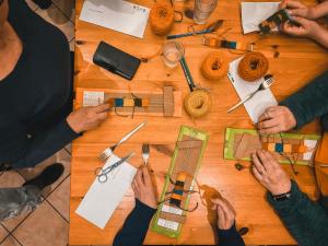 un gruppo di persone che fanno lavori artigianali su un tavolo di legno di Casa del Parco Adamello a Cevo