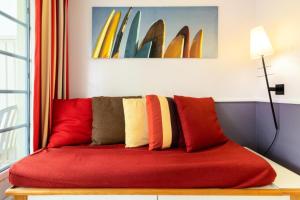 - un canapé rouge avec des oreillers colorés dans l'établissement Village Moliets - maeva Home - Appartement 2 pièces 4 personnes - Confort MAE-9764, à Moliets-et-Maa 23 autres photos