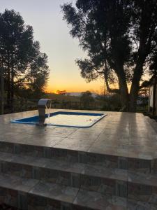 a swimming pool with a sunset in the background at Sítio paiol Velho in Cristina
