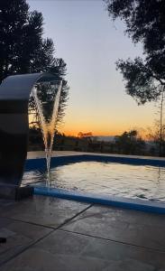a water fountain with the sun setting in the background at Sítio paiol Velho in Cristina