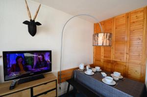 ein Wohnzimmer mit einem TV und einem Tisch mit Tassen und einer Uhr in der Unterkunft Résidence Chaviere - 2 Pièces pour 4 Personnes 434 in Les Menuires