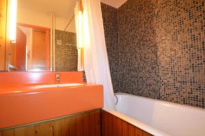 ein Badezimmer mit einer Badewanne, einem Waschbecken und einem Spiegel in der Unterkunft Résidence Chaviere - 2 Pièces pour 4 Personnes 434 in Les Menuires