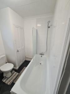 a bathroom with a white tub and a toilet at Double Rooms with shared bathroom in Gillingham