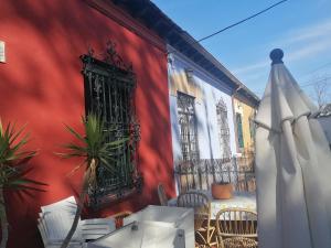 ein rotes Gebäude mit einem Tisch, Stühlen und einem Regenschirm in der Unterkunft casa la salud in Málaga