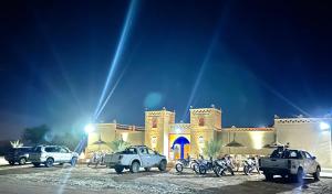 ein Gebäude mit nachts vor ihm geparkt in der Unterkunft Porte De Sahara Ouzina in Ouzina