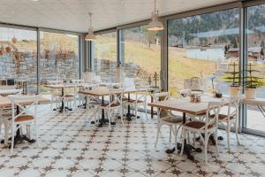 a restaurant with tables and chairs and large windows at Emma's B&B LUNGERN - Self Check-in Hotel in Lungern