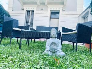 una statua seduta sull'erba di fronte alle sedie di Villa Martina Retreat a Lecco