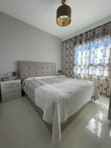 Un dormitorio blanco con una cama grande y una ventana en Elisa Bay apartment Mil Palmeras, en Torre de la Horadada