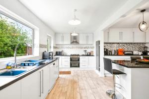 eine Küche mit weißen Schränken und einem großen Fenster in der Unterkunft Exmoor Close in North Hykeham