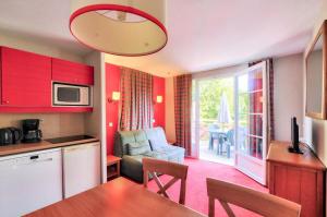 eine Küche und ein Wohnzimmer mit roten Schränken und einem Tisch in der Unterkunft La résidence du Lac - maeva Home - Appartement 2 Pièces 4 Personnes - Sél 714 in Monflanquin