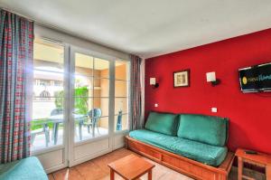 een woonkamer met een groene bank en een balkon bij La résidence du Lac - maeva Home - Appartement 2 Pièces 5 Personnes - Sél 294 in Monflanquin