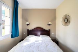une chambre avec un grand lit avec des rideaux bleus dans l'établissement Résidence Les Belles Rives - maeva Home - Appartement 2 pièces 5 personnes - Confort MAE-4384, à Argentat 17 autres photos