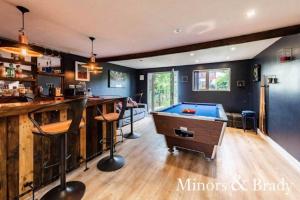 a room with a bar and a pool table at Modern terrace with large garden & standalone bar in Norwich