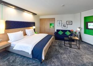ein Schlafzimmer mit einem großen Bett und einem Sofa in der Unterkunft Holiday Inn Stuttgart, an IHG Hotel in Stuttgart