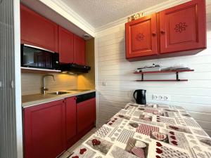 a kitchen with red cabinets and a sink and a table at Résidence Villaret - Grand studio 4 personnes aux Menuires - accès 3 Vallées MAE-5734 in Les Menuires