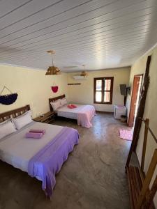 two beds in a large room with two windows at Pousada Varanda da Serra in Cavalcante