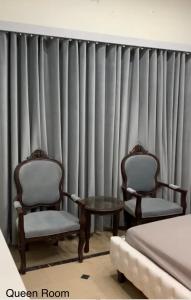 dos sillas y una mesa frente a una cortina en Holiday Home Family & Groups, en Gujrāt