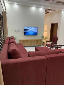 Holiday Home Family & Groups في Gujrāt: غرفة معيشة مع أريكة حمراء وتلفزيون بشاشة مسطحة
