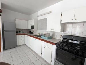 a kitchen with white cabinets and a black stove at Montserrat Mountain View Retreat in Cudjoe Head