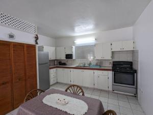 a kitchen with white cabinets and a table with a tablecloth on it at Montserrat Mountain View Retreat in Cudjoe Head