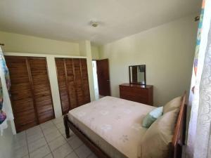a bedroom with a bed and a dresser at Montserrat Mountain View Retreat in Cudjoe Head
