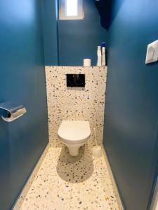a bathroom with a toilet in a blue wall at Les Appartements du Grand Hôtel Clichy Paris in Clichy