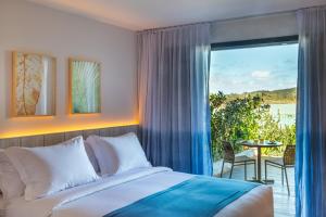 a bedroom with a bed and a balcony with a view at Hotel Aretê in Búzios
