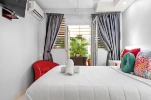 1 dormitorio con 1 cama blanca y 1 silla roja en Prime Location at Condado Beach Queen Studio - Apt 10, en San Juan