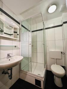 ein Bad mit einer Dusche, einem WC und einem Waschbecken in der Unterkunft Pension Liechtenstein in Wien