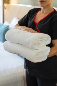 a woman holding a stack of folded towels at Hotel Plaza Central Canning in Ezeiza