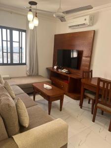 a living room with a couch and a flat screen tv at RED-22- ALSALAM suites in Salalah