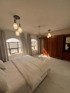 a bedroom with a large white bed and two windows at RED-22- ALSALAM suites in Salalah