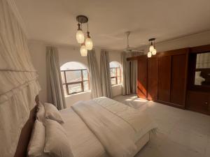 a bedroom with a large white bed and two windows at RED-22- ALSALAM suites in Salalah