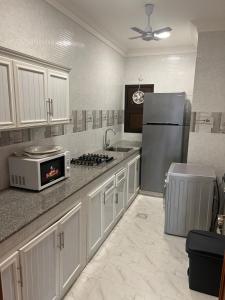 a kitchen with white cabinets and a stainless steel refrigerator at RED-22- ALSALAM suites in Salalah